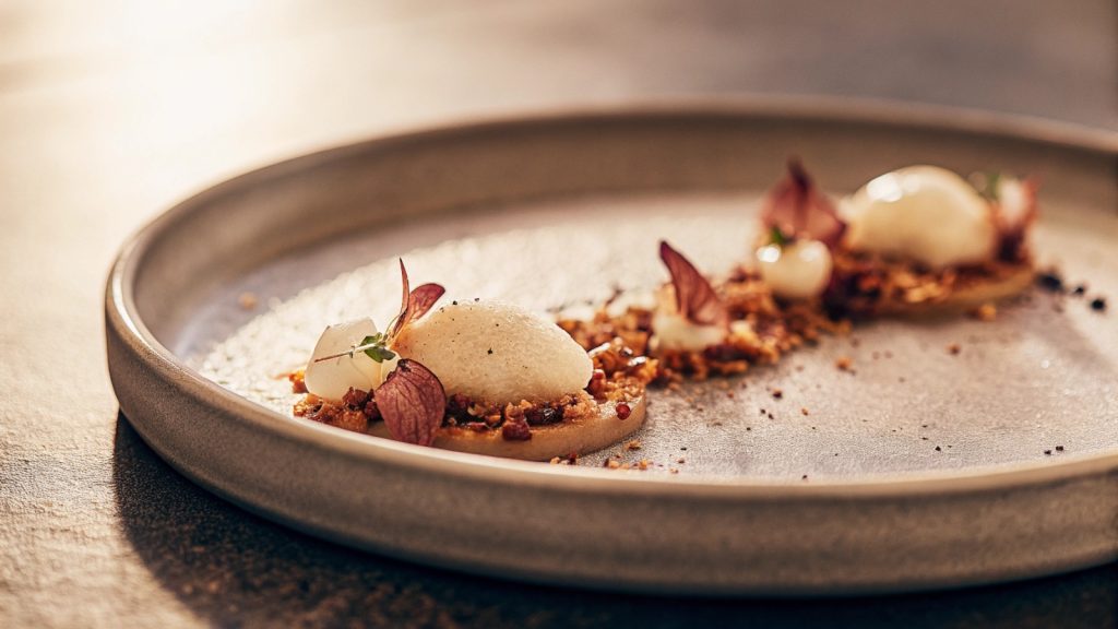 Contemporary plated dish with minimalist presentation, focus on texture and composition, neutral background, no people