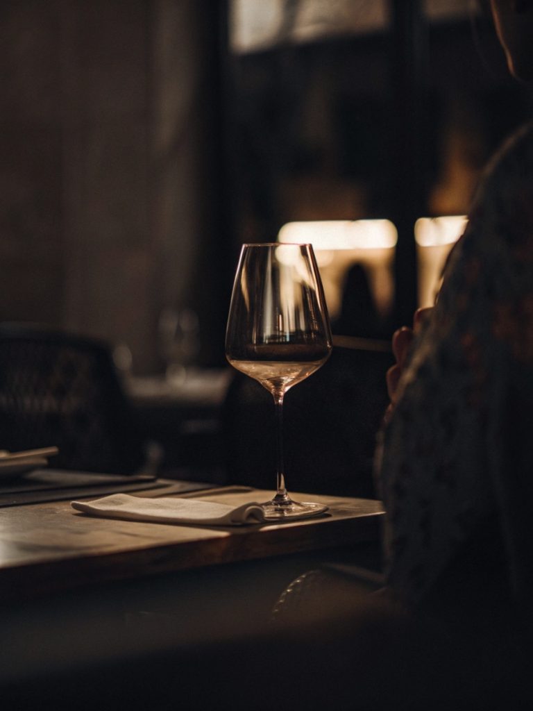 Detalhe de mesa com vinho e ambiente acolhedor que representa a experiência gastronómica